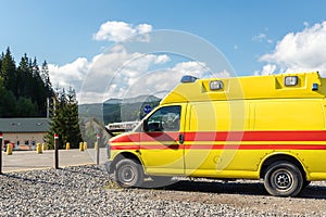 Side view of yellow ambulance rescue ems van car parked near countryside rural road at highland mountain resort area