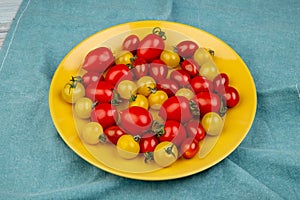 side view of yellow and red tomatoes in plate on blue cloth background