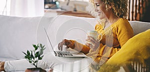 Side view of young adult woman have relax leisure at home using laptop and drinking. MOdern female people with computer sitting on