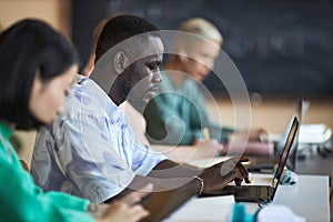 Side view of young African American student of highschool using laptop