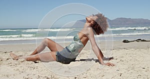 Side view of young African american woman relaxing on the beach 4k