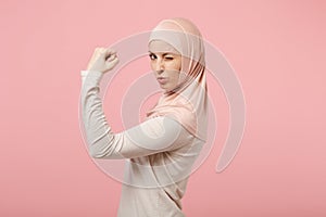 Side view of young arabian muslim woman in hijab light clothes posing isolated on pink wall background. People religious