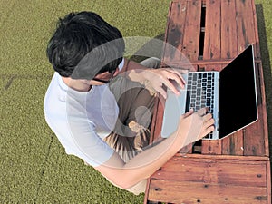 Side view of young Asian man using computer laptop at outdoors. Internet of things concept