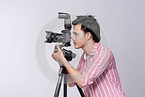 Side view of young asian photographer holding digital camera, while working in studio