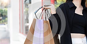 Side view of young Asian woman holding shopping bags on Black Friday while standing in the mall area copy space