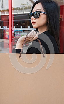 Side view of young Asian woman holding shopping bags on Black Friday while standing in the mall area copy space