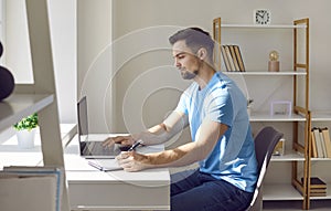 Young business man working with laptop computer at home or at office and writing.