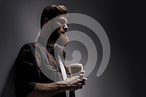 Side view of young bearded man drinking morning coffee
