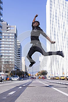 Side view young black man wearing casual clothes jumping in urban background. Lifestyle concept. Millennial african guy wearing