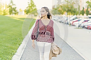 Side view of young content ethnic female with makeup in trendy outfit on city pavement