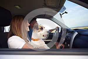 Side view of young couple and dog traveling by car