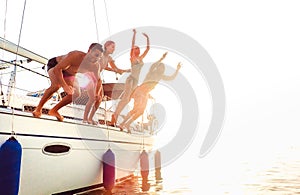 Side view of young crazy friends jumping from sailboat on sea ocean trip - Men and women having summer fun together