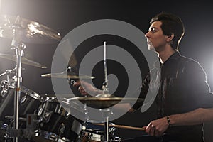 Side View Of Young Drummer Playing Drum Kit In Studio