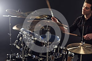 Side View Of Young Drummer Playing Drum Kit In Studio