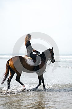 side view of young female equestrian riding horse