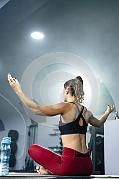 Side view of young fit woman in sportswear doing yoga at gym