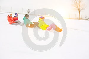 Side view of young friends sledging on snow covered slope