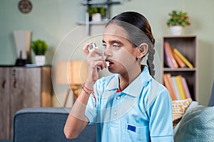 Side view young girl kid using asthma medication inhaler after taking deep breath - Concept of asthmatic teenager kids