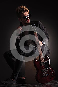 Side view of a young guitarist sitting and looking back