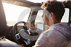 Side view of young Hispanic man driving with sunroof open