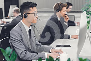 Side view of young male call center operators working together