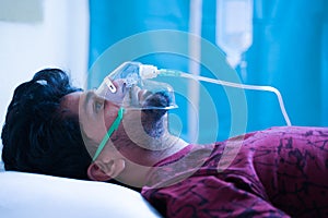 Side view on young man breathing on ventilator oxygen mask at hospital due coronavirus covid-19 dyspnea or breathlessness -