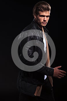 Side view of a young man in leather jacket is walking
