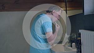 Side view of young man looking in mirror, brushing teeth, camera tracking