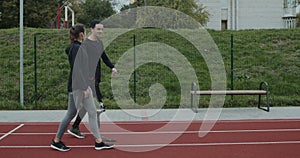 Side view of young man with prosthetic running blade talking to woman outdoors. Male person with amputed leg chatting