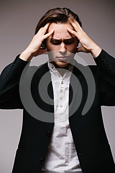 Side view of young man in shirt touching his head and keeping eyes closed