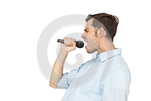 Side view of a young man singing into microphone