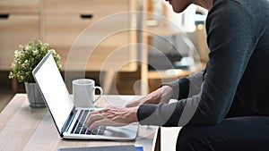 Young man siting on sofa and using laptop computer at home.