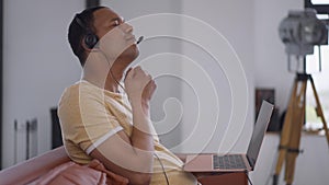 Side view of young man stretching neck spasm typing on laptop keyboard in home office. Concentrated overworking African