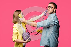 side view of young man and woman holding rotary phones and handsets for each other isolated