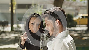 Side view of young muslim couple eating lunch in park.