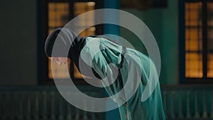 Side view of a young muslim woman bowing in prayer in a mosque at night