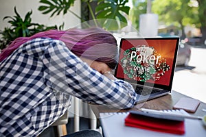 Side view of a young pink hair woman keyboarding on laptop computer with poker online on a screen while sitting in cafe