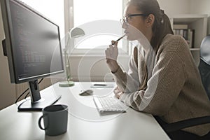 Side view of young programmer working on computer codes from her home