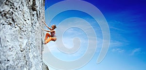 Young slim woman rock climber climbing on the cliff