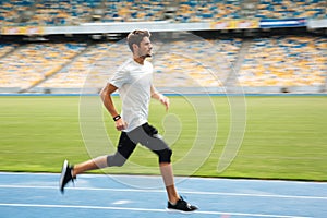 Side view of a young sportsman running on a racetrack