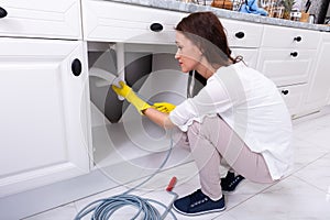 Woman Cleaning Clogged Sink Pipe