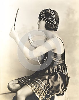 Side view of young woman holding powder puff and mirror