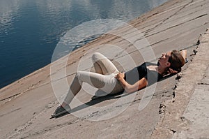 Side view young woman lying on a wooden jetty enjoying the sunshine,tourist girl in bright summer glasses lying on jetty by river photo