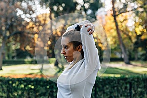 Side view of a young woman stretching her arms while doing sports in the middle of nature photo