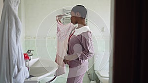 Side view young woman trying on dress in bathroom thinking in the morning getting ready. Portrait of slim African