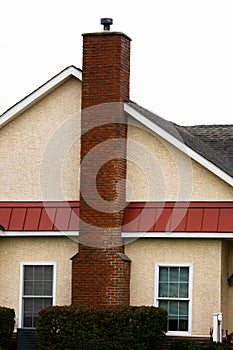 Side of white house with tall red brick chimney outdoor