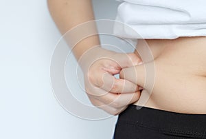 Side of woman hand catching fat body belly paunch , diabetic risk factor .