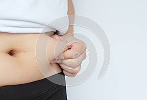 Side of woman hand catching fat body belly paunch , diabetic risk factor .