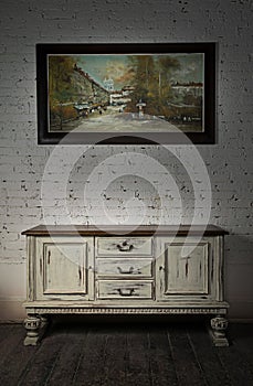 Sideboard and hanged painting over wooden floor and bricks wall