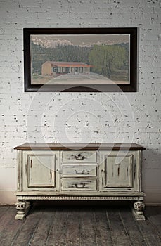 Sideboard and hanged painting over wooden floor and bricks wall